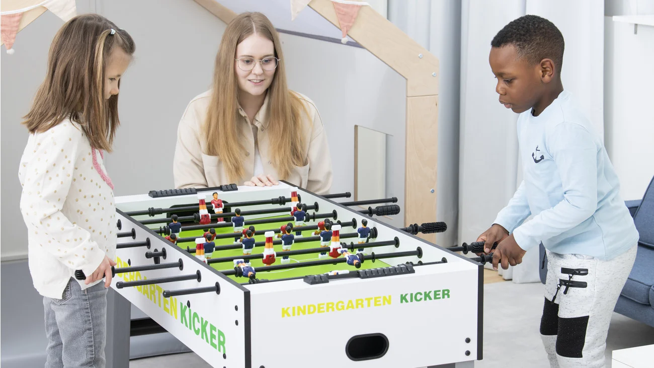 Kinder und Betreuerin am Kindergarten Tischkicker